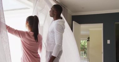 Mutlu ve çeşitli çiftin evdeki pencerelerden fotokopi çekerek dışarı baktığı bir video. Mutluluk, kapsayıcılık, boş zaman, birliktelik ve ev hayatı..