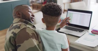 African american father with son learning together with laptop. Spending quality time together, army and patriotism concept.