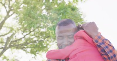 Happy african american father and his son embracing in garden. Spending quality time at home.
