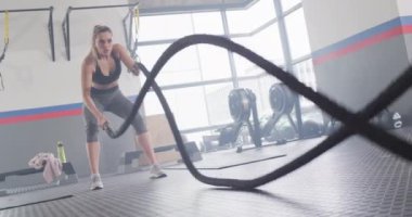 Video of determined caucasian woman working out at a gym with battling ropes. Exercise, fitness and healthy lifestyle.