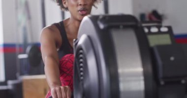 Video of determined african american woman using rowing machine working out at gym. Exercise, fitness and healthy lifestyle.