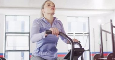 Video of determined caucasian woman on exercise bike working out at a gym. Exercise, fitness and healthy lifestyle.