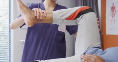 Çeşitli kadın fizyoterapist ve hastanede bacağa uygulanan fizik tedavi seansındaki yaşlı erkek hasta. Tıp, sağlık, yaşam tarzı ve hastane konsepti.