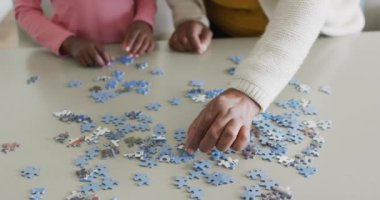 Afro-Amerikalı torun ve büyükannenin elleri evde yapboz yapıyor, uzayı kopyalıyor. Bilim, eğitim, öğrenme, aile ve ev hayatı.