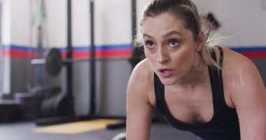 Close up video of determined caucasian woman doing push ups working out at a gym. Exercise, fitness and healthy lifestyle.