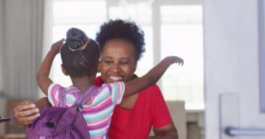 Afrikalı Amerikalı torunun okul çantasıyla eve gelip mutlu büyükannesine sarılmasının videosu. Çocukluk, aile ve aile hayatı.