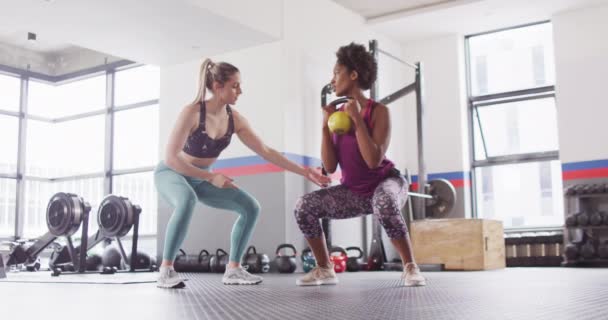 Video Diverse Female Fitness Trainer Instructing Woman Doing Squats Kettlebell — Vídeo de Stock