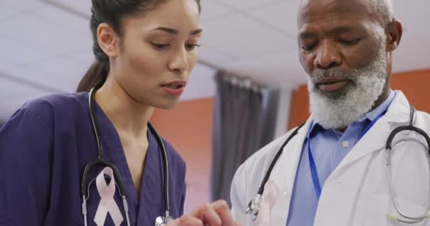 Two Diverse Male Female Doctors Wearing Cancer Awareness Ribbons Talking — Stock Video
