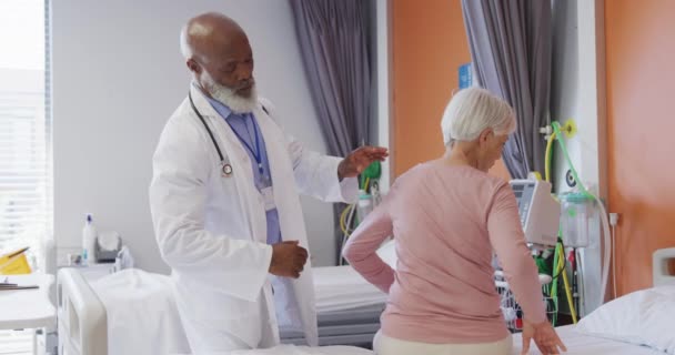 非洲裔美国男性医生在医院检查老年高加索女性病人的背部 生活方式和医院概念 — 图库视频影像