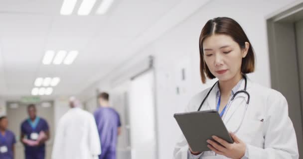 Wideo Przedstawiające Uśmiechniętą Azjatycką Lekarkę Tabletką Korytarzu Szpitalnym Przestrzenią Kopiowania — Wideo stockowe