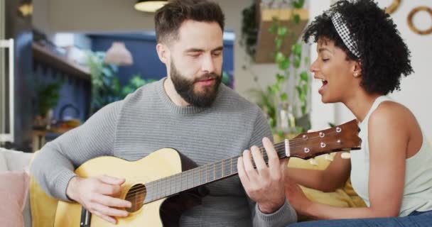 Video Happy Diverse Couple Relaxing Living Room Man Playing Guitar — Stockvideo
