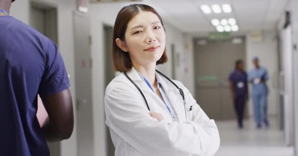 Wideo Przedstawiające Uśmiechniętą Azjatycką Lekarkę Stojącą Zatłoczonym Szpitalnym Korytarzu Przestrzeń — Wideo stockowe
