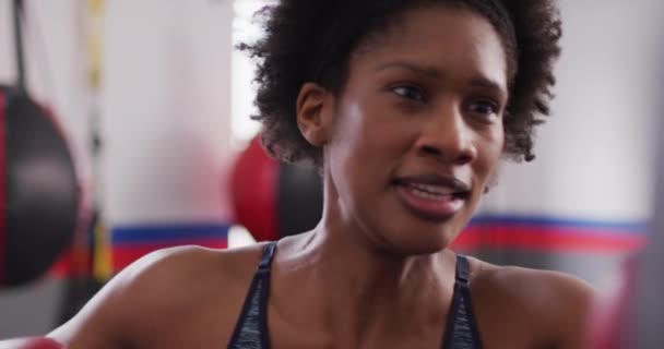自信を持って決定されたアフリカ系アメリカ人女性のビデオボクシンググローブトレーニングジムでパンチバッグで フィットネス 健康的なライフスタイル — ストック動画