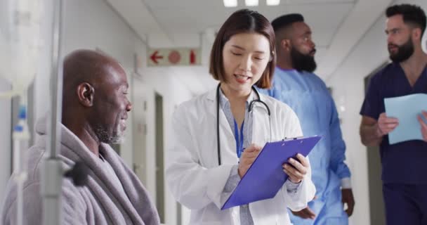 不同的男病人和女医生在繁忙的医院走廊里写便条的视频 医疗和保健服务 — 图库视频影像
