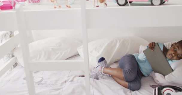Счастливая Африканская Американская Девушка Использующая Планшет Лежащий Двухъярусной Кровати Дома — стоковое видео