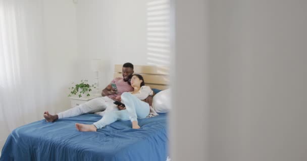 Happy Diverse Couple Using Smartphone Lying Bedroom Spending Quality Time — Vídeo de stock