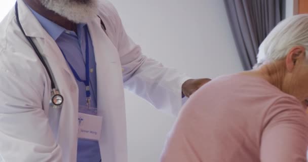 Αφροαμερικανός Γιατρός Που Εξετάζει Την Πλάτη Μιας Ηλικιωμένης Καυκάσιας Ασθενούς — Αρχείο Βίντεο