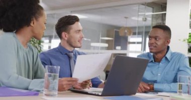 Ofiste iş tartışan ve dizüstü bilgisayar kullanan mutlu iş adamları, yavaş çekim. Modern ofis, iş ve finans sektöründe çalışmak.