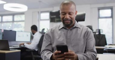 Akıllı telefon kullanan ve ofiste çalışan bir grup mutlu iş adamı, yavaş çekim. Küresel iş, finans ve modern ofiste çalışma.