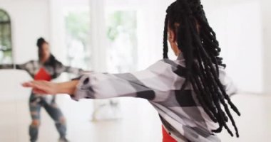 Biracial female dancer dancing alone in front of mirror in dance studio, slow motion. Hobby, art and dance studio concept.