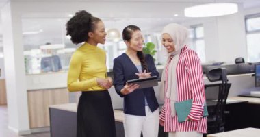 Tablet kullanan ve ofiste konuşan bir grup iş adamı, yavaş çekim. Küresel iş, finans ve modern ofiste çalışma.