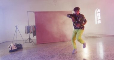Happy biracial male dancer dancing alone in dance studio, slow motion. Hobby, art and dance studio concept.