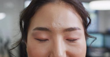 Ofiste kameraya bakan Asyalı iş kadınının portresi, ağır çekim. Küresel iş, finans ve modern ofiste çalışma.