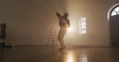 Portrait of biracial male dancer dancing in dance studio, slow motion. Hobby, art and dance studio concept.