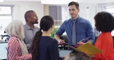 Belgeleri tutan ve ofiste konuşan bir grup iş adamı, yavaş çekim. Küresel iş, finans ve modern ofiste çalışma.