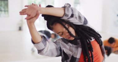 Biracial female dancer stretching with diverse colleagues in dance studio, slow motion. Hobby, art and dance studio concept.