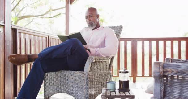 Happy Senior African American Man Spending Time Log Cabin Reading — Αρχείο Βίντεο