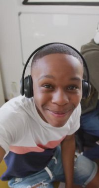 Vertical video of portrait of happy diverse male teenage friends making vlog at home. Spending quality time at home together.