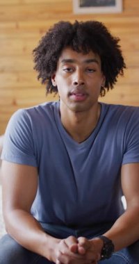 Afro-Amerikan bir adamın kameraya bakıp odunlukta gülümseyişinin dikey videosu. Boş zaman ve ev hayatı kavramı.