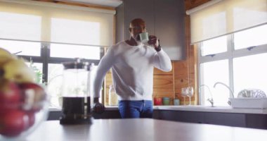 Senior african american man spending time in log cabin and drinking coffee, slow motion. Free time, domestic life and leisure concept.