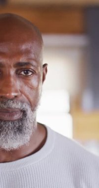 Vertical video of portrait of happy senior african american man spending time in log cabin. Free time, domestic life and nature concept.