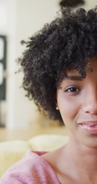 Vertical half face video portrait of laughing biracial woman with afro, with copy space. Happiness, relaxation and domestic life.
