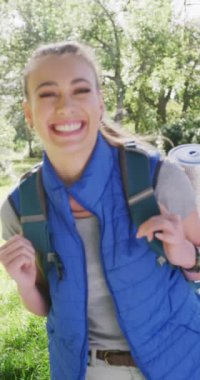Vertical video of portrait of happy caucasian woman in park, slow motion. Nature, hiking and park concept.
