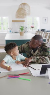 Vertical video of african american male soldier and his son working and doing homework. Spending quality time at home.