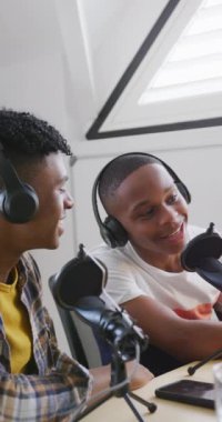 Vertical video of happy african american male teenage friends making vlog at home. Spending quality time at home together.