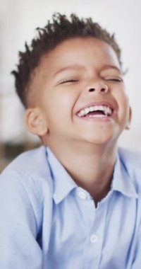 Vertical video of portrait of happy african american boy looking at camera and smiling. Spending quality time at home.