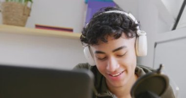 Happy diverse male teenage friends using laptop and recording podcast, slow motion. Spending quality time at home together.