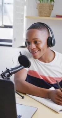 Vertical video of happy african american male teenage boy making vlog at home. Spending quality time at home alone.