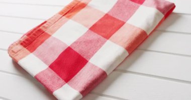 Close up of folded red and white checkered blanket on white background with copy space. Picnic day, food and nature concept.