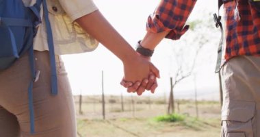 Sırt çantalı, güneşli bir günde yürüyüş yapan mutlu Afro-Amerikan çift. Ağır çekimde. Yaşam tarzı, kırsal ve doğa konsepti.