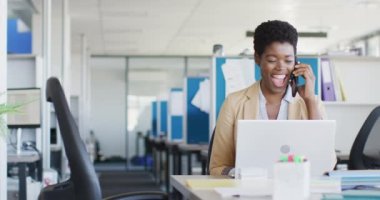 African american businesswoman using laptop and smartphone at office, slow motion. Working at office, business concept.