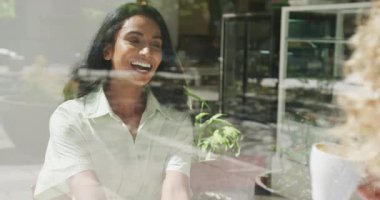Happy diverse couple sitting at table and talking in cafe. City break, travel, local business and hospitality concept.