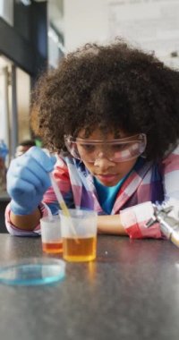 Okul sınıfındaki çeşitli öğrencilerin sıralarda dikey videoları. Eğitim, kapsayıcılık, okul ve öğrenme kavramı.