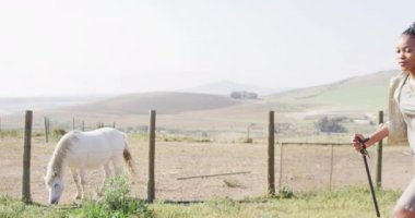 Sırt çantalı mutlu Afro-Amerikan çifti yürüyüş direkleri ile yürüyüş yapıyorlar, ağır çekimde. Açık hava yaşam tarzı, kırsal ve doğa kavramı.