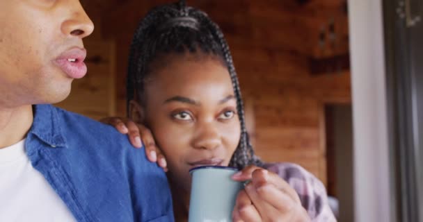快乐的非洲裔美国夫妇看着窗外 在木屋里喝咖啡 动作缓慢 生活方式 家庭生活 农村和自然概念 — 图库视频影像