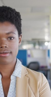 Vertical video of portrait of happy african american businesswoman in office. Global business and modern office concept.